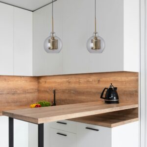 Suspension boule verre et meÌtal dans cuisine blanche et bois